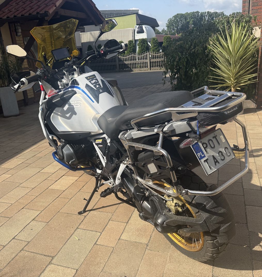 Motocykl turystyczny BMW R 1250 GS Adventure w biało-niebiesko-czerwonym malowaniu, wyposażony w liczne akcesoria off-road.