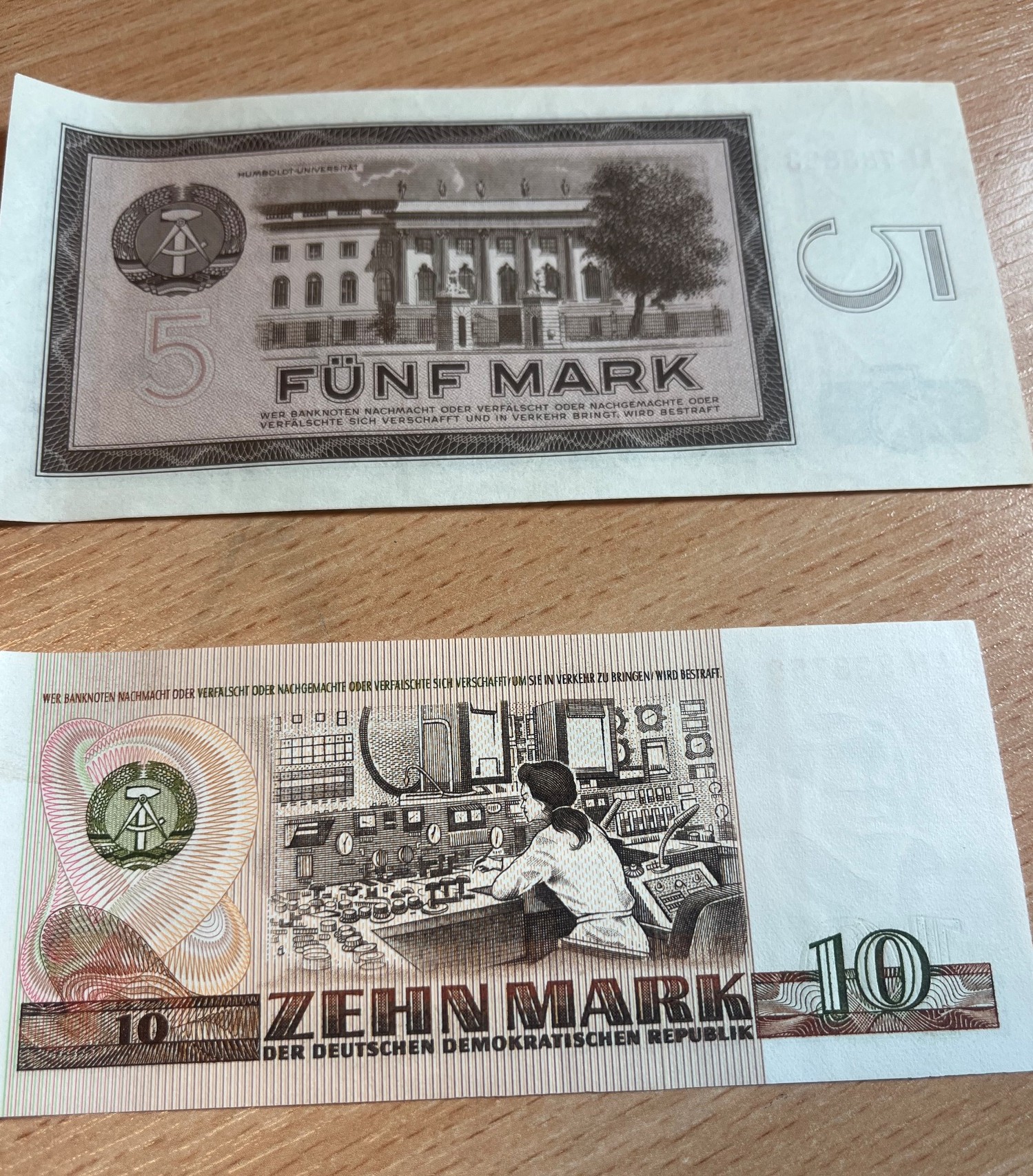 Odwrotna strona banknotów z NRD o nominale 5 marek z grafiką uniwersytetu oraz 10 marek z grafiką centrum sterowania.