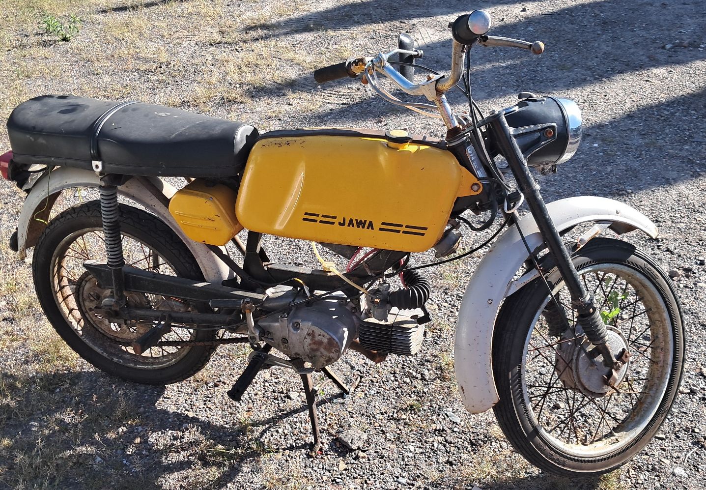 Widoczny jest motorower, koła, układ kierowniczy, siedzenie