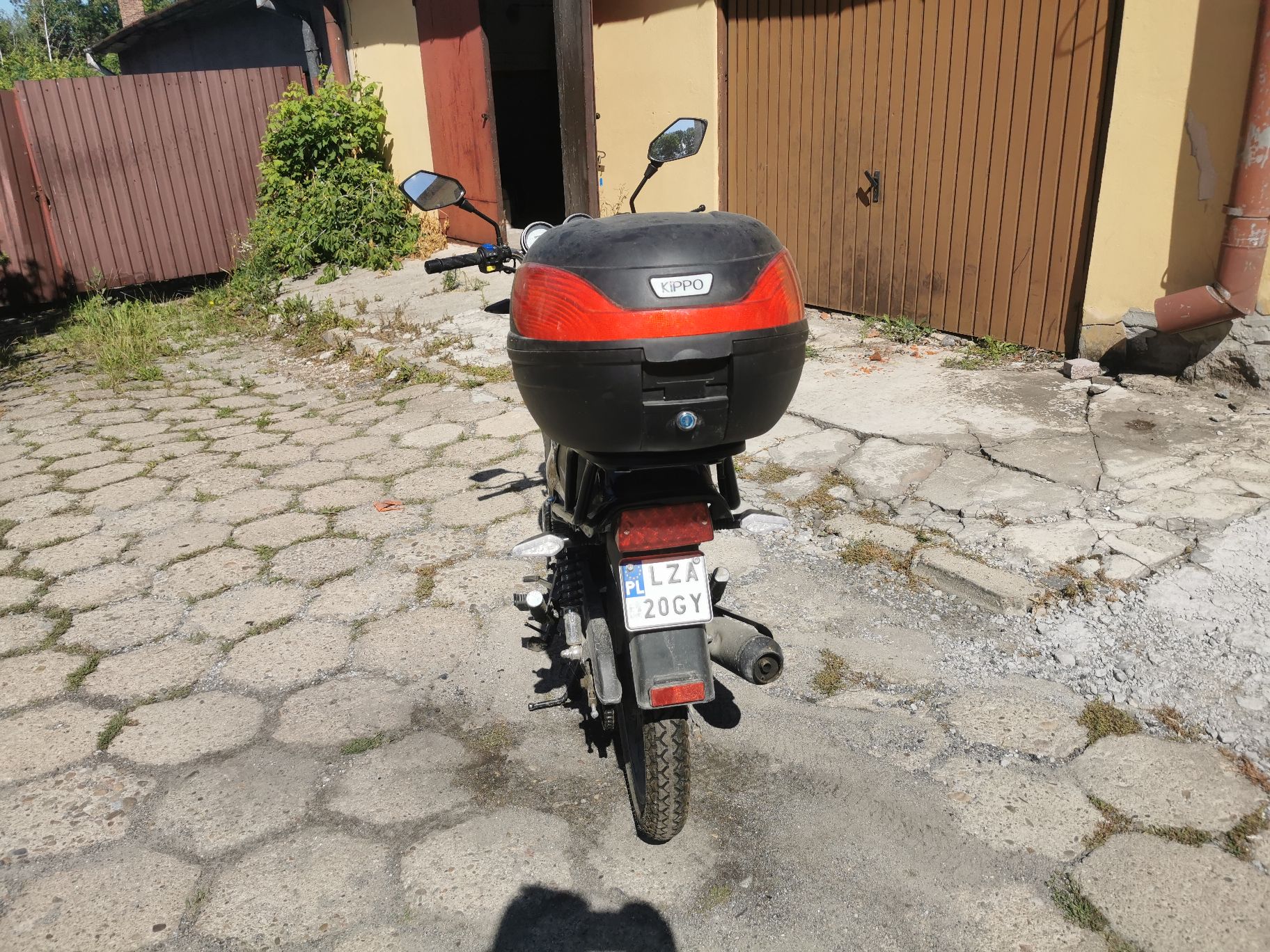 Tył pojazdu. Kufer podróżny, lampy, tłumik spalin, lusterka wsteczne. Brak uszkodzeń.