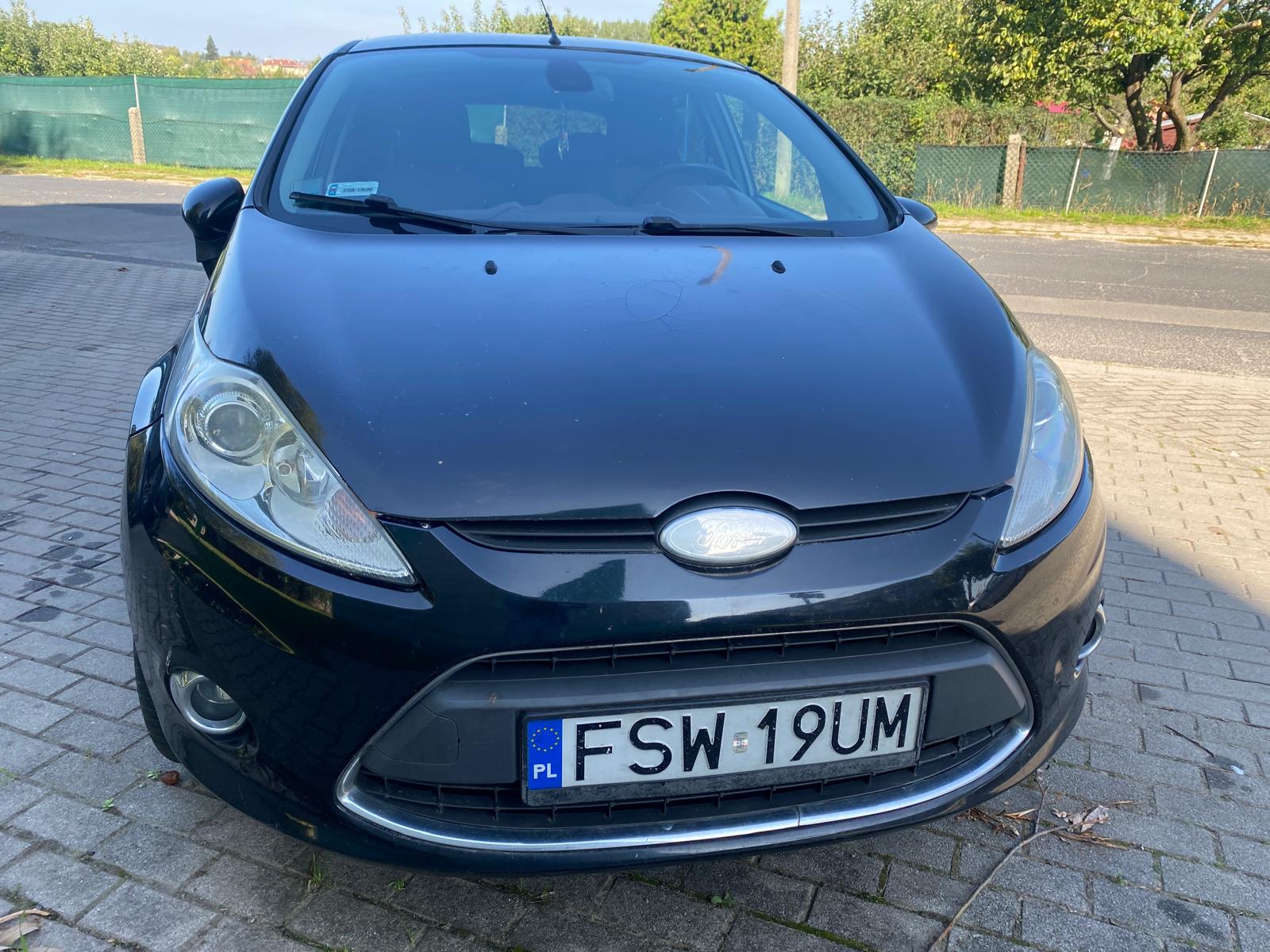 Przód Forda Fiesty koloru czarnego. Zderzak i lusterka boczne koloru czarnego.