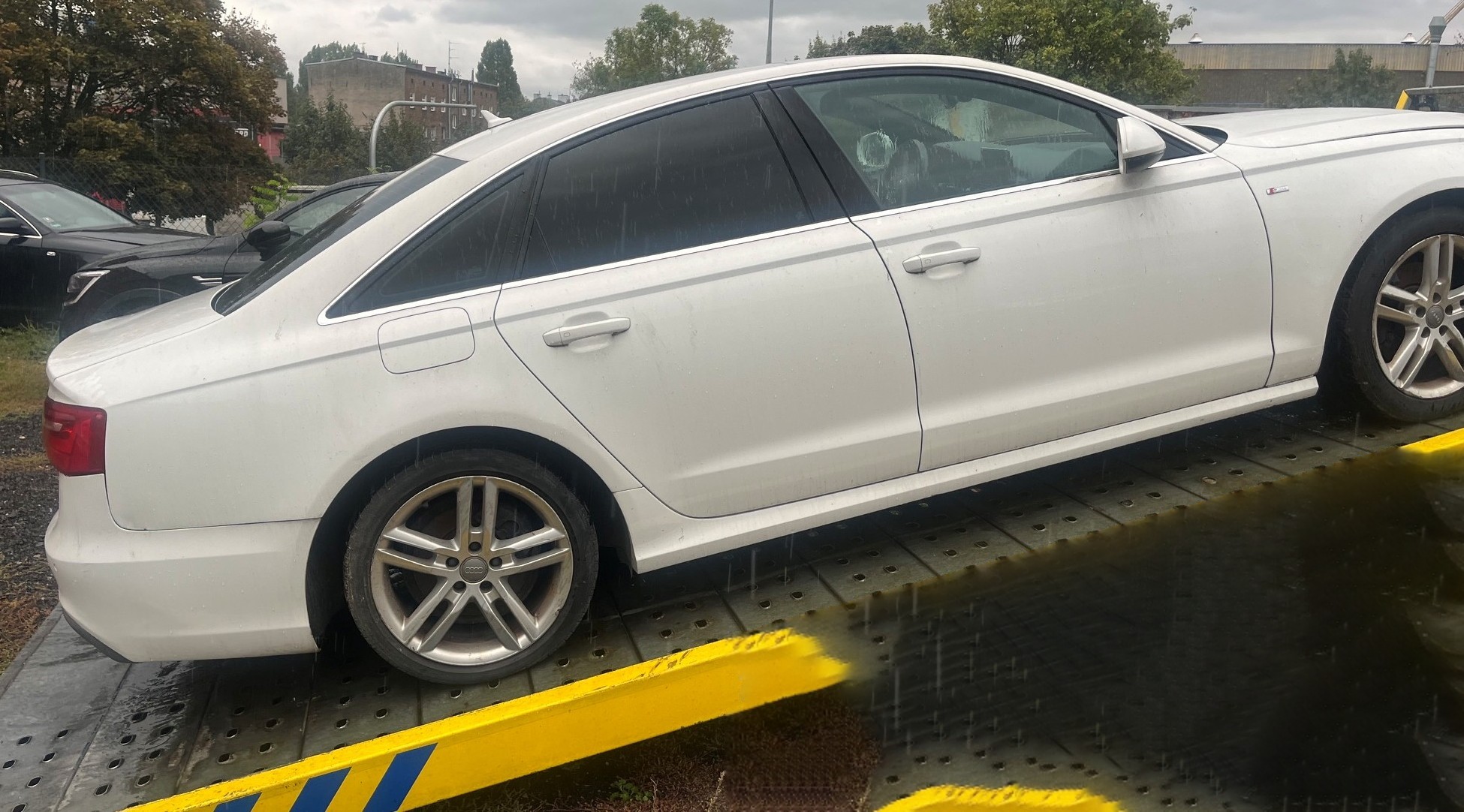 Prawy bok Audi A6 stojącego na pochylonym, metalowym najeździe lawety.