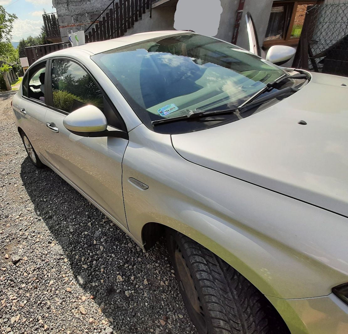 Srebrny FIAT TIPO widoczny z prawej strony z przednią szybą, lusterkiem bocznym oraz wycieraczkami.