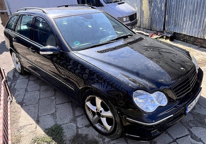 Samochód Mercedes-Benz C 180 w kolorze czarnym widoczny od przodu z lewej strony.