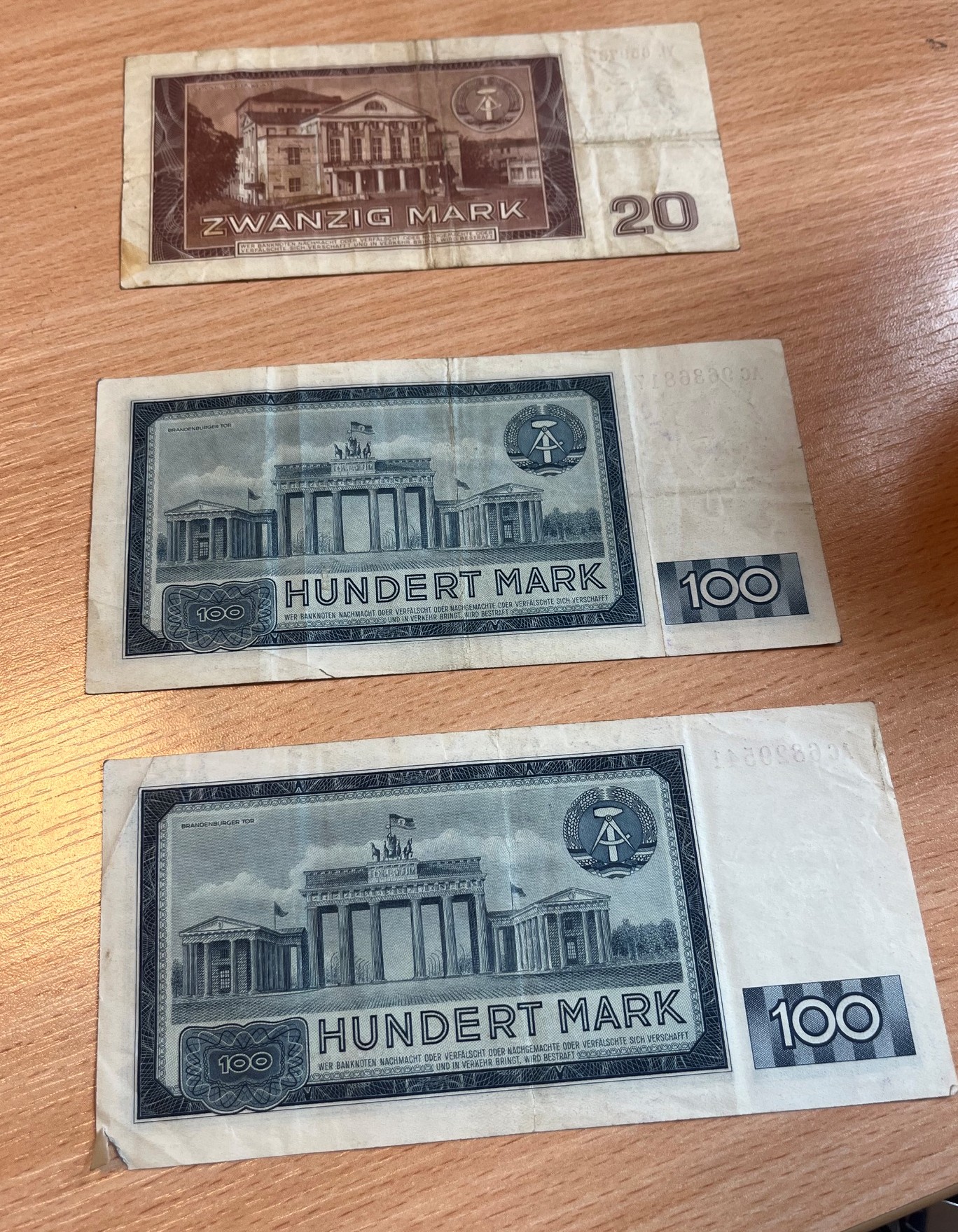 Rewersy trzech banknotów NRD z 1964 r.: jeden o nominale 20 marek oraz dwa o nominale 100 marek.