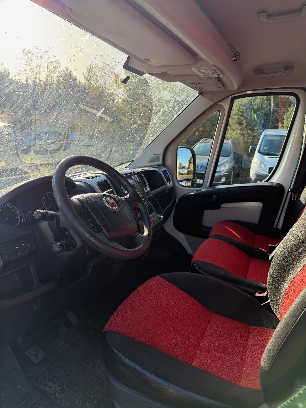 Biały Fiat Ducato, ujęcie przedniej części wnętrza kabiny pojazdu.