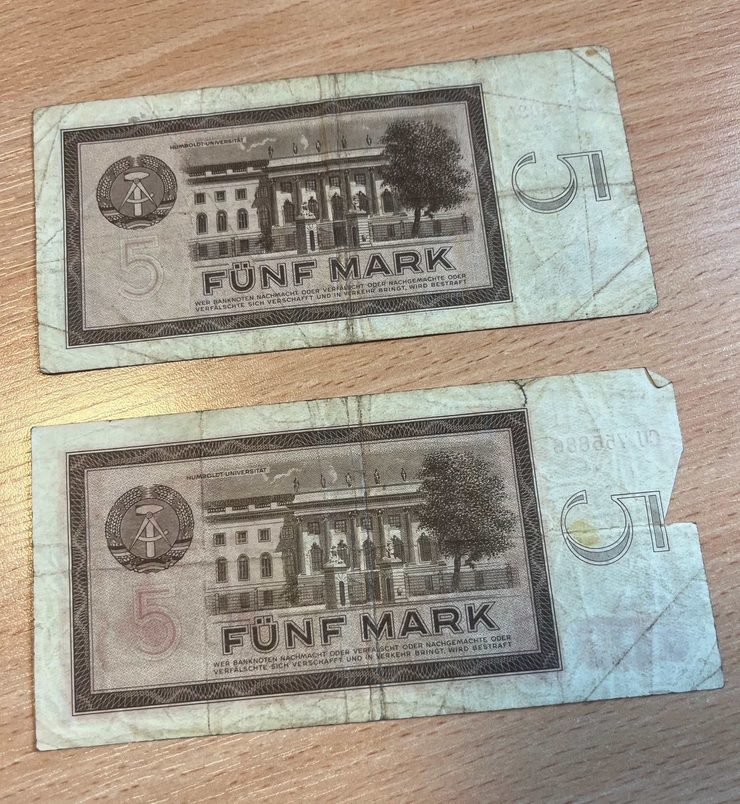 Rewersy dwóch banknotów o nominale 5 marek NRD z emisji z 1964 roku, ułożone pionowo jeden pod drugim.