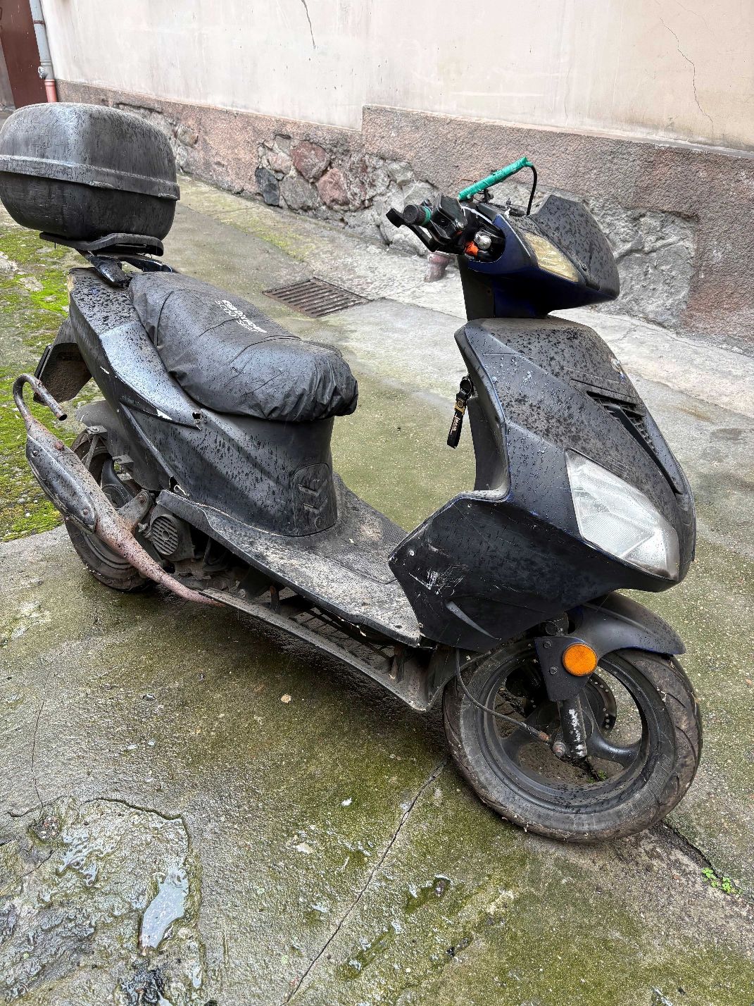 Motorower koloru czarnego wraz z szarym kufrem, widok prawego boku