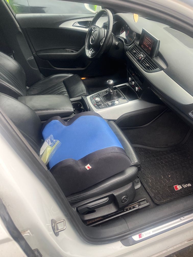Wnętrze Audi A6 z widoczną na fotelu pasażera podkładką dziecięcą (przynależność do samochodu).