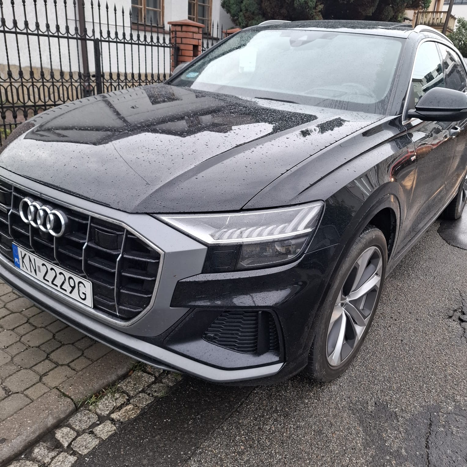 Czarny samochód Audi Q5 zaparkowany z widocznymi kroplami wody na karoserii.
