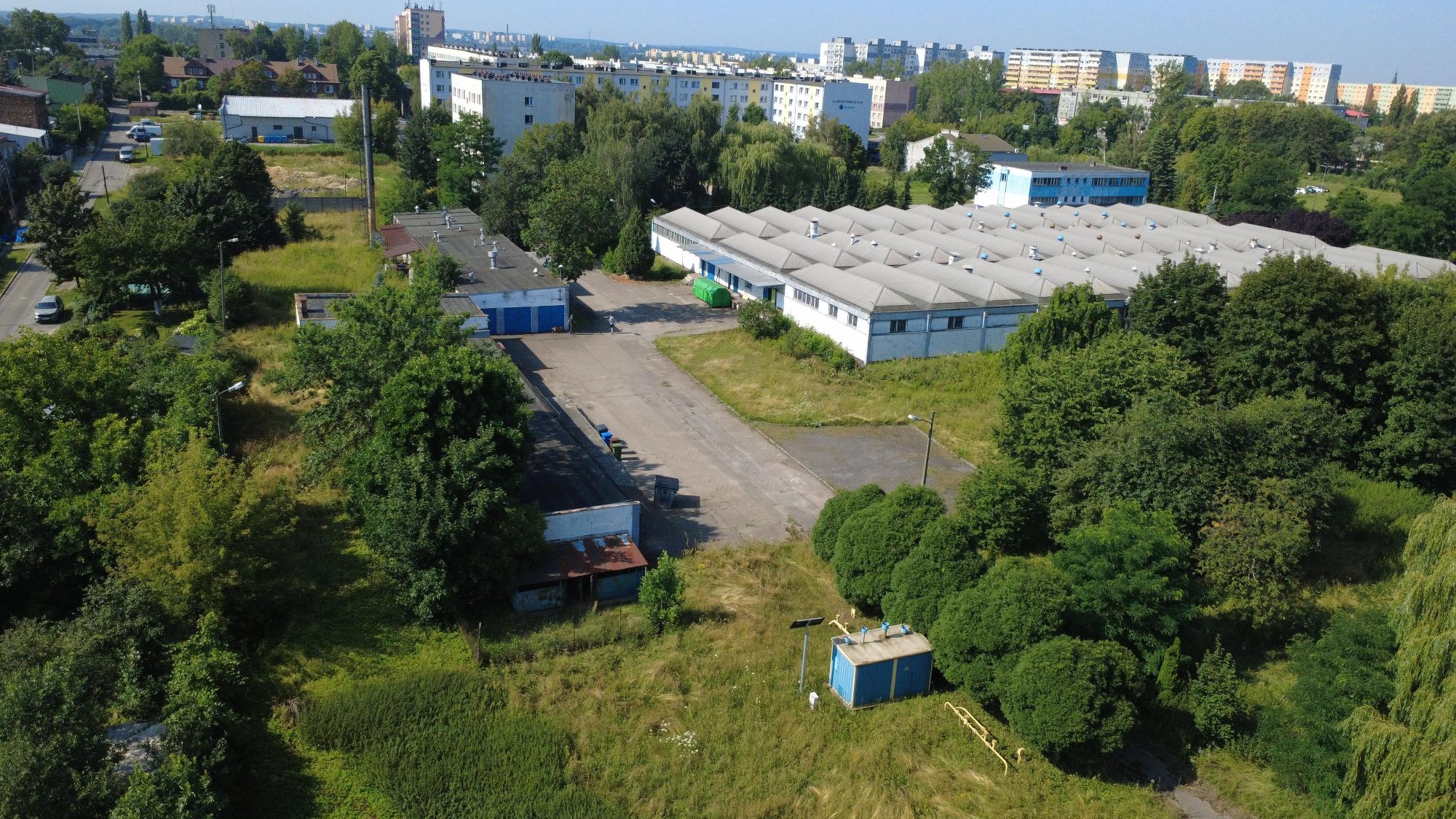 Widok kompleksowy nieruchomości z ternami zielonymi i zabudową.