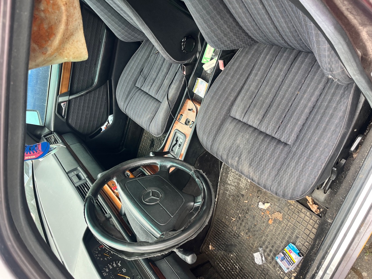 Wnętrze Mercedesa z materiałową tapicerką, automatyczną skrzynią biegów oraz drewnianym wykończeniem.