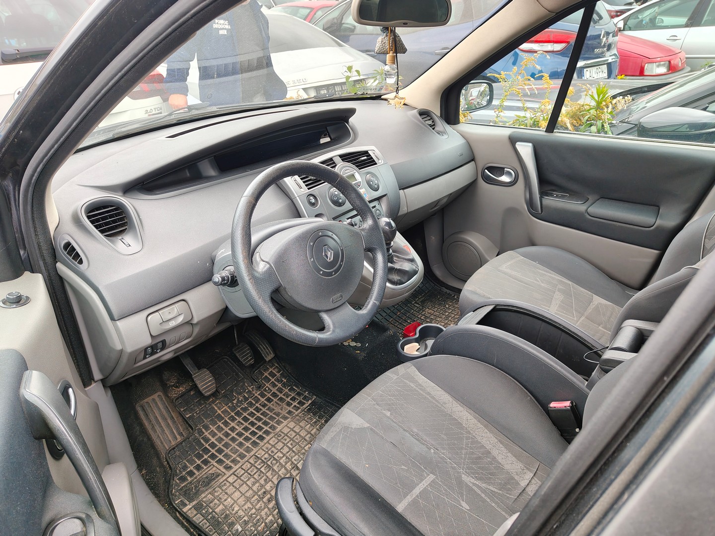Wnętrze samochodu z kierownicą Renault, przednimi fotelami i deską rozdzielczą oraz trzema rzędami foteli i przestronną kabiną.
