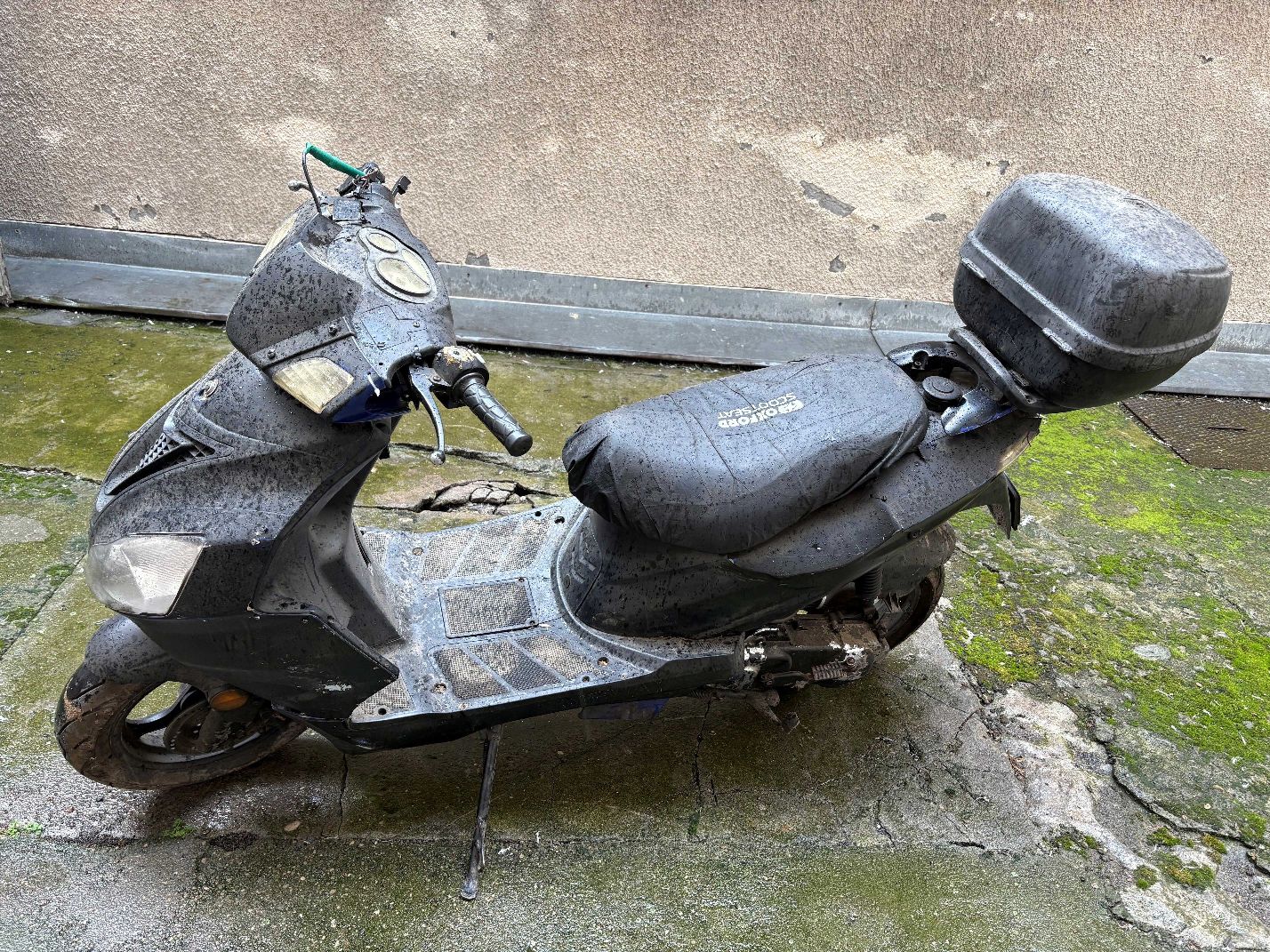 Motorower koloru czarnego wraz z szarym kufrem, widok lewego boku