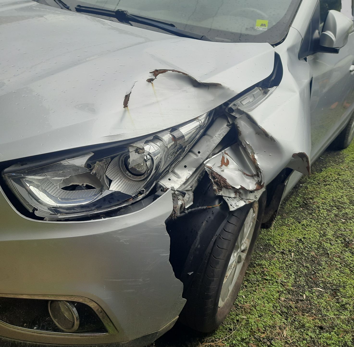 Samochód osobowy, widok z przodu od lewej strony, uszkodzone nadkole, maska pojazdu oraz lampa lewa