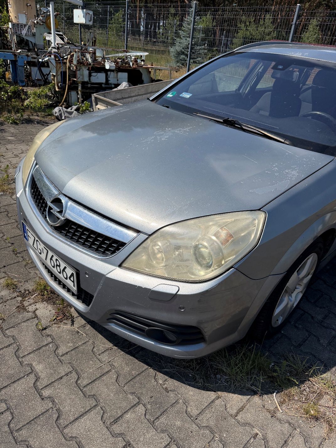 Szary Opel Vectra. Ujęcie uszkodzonej maski. Widoczne odpryski powłoki lakieru.