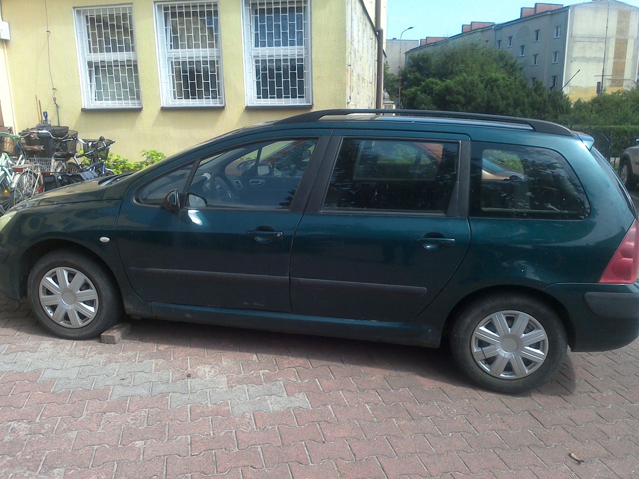 Widok zielonego Peugeota 307 z lewej strony. Stan powłoki lakierniczej oraz elementów nadwozia.