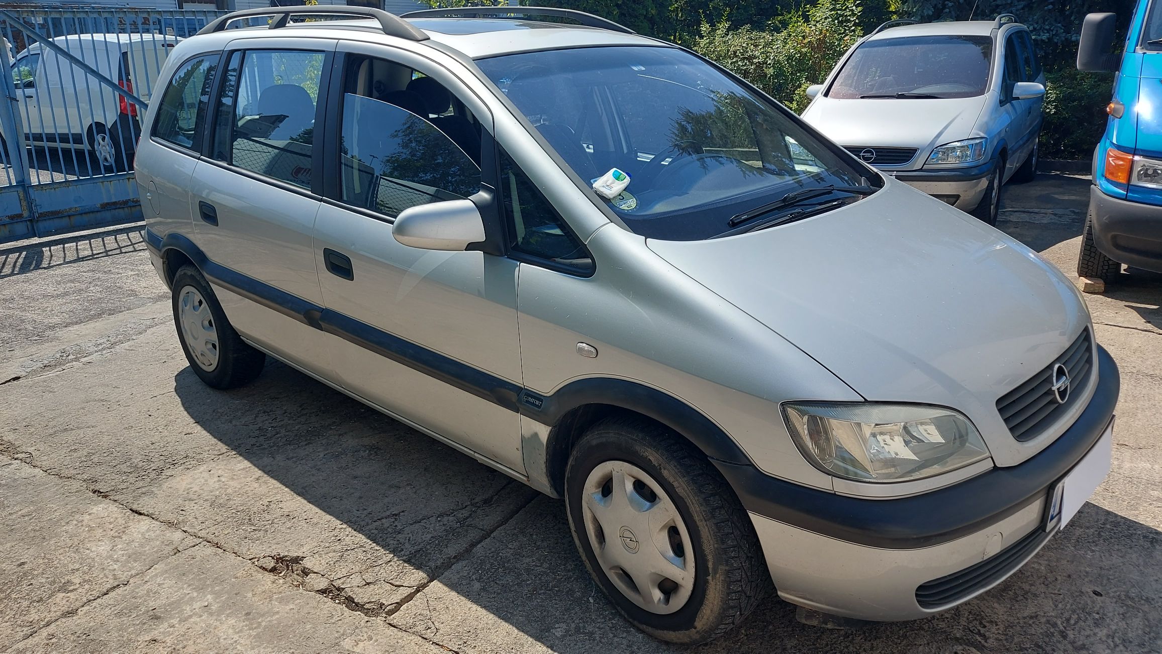 Srebrny Opel Zafira, widok na przód i lewy bok auta.