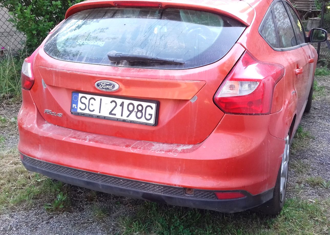 Tylna cześć czerwonego samochodu stojącego na podwórzu
