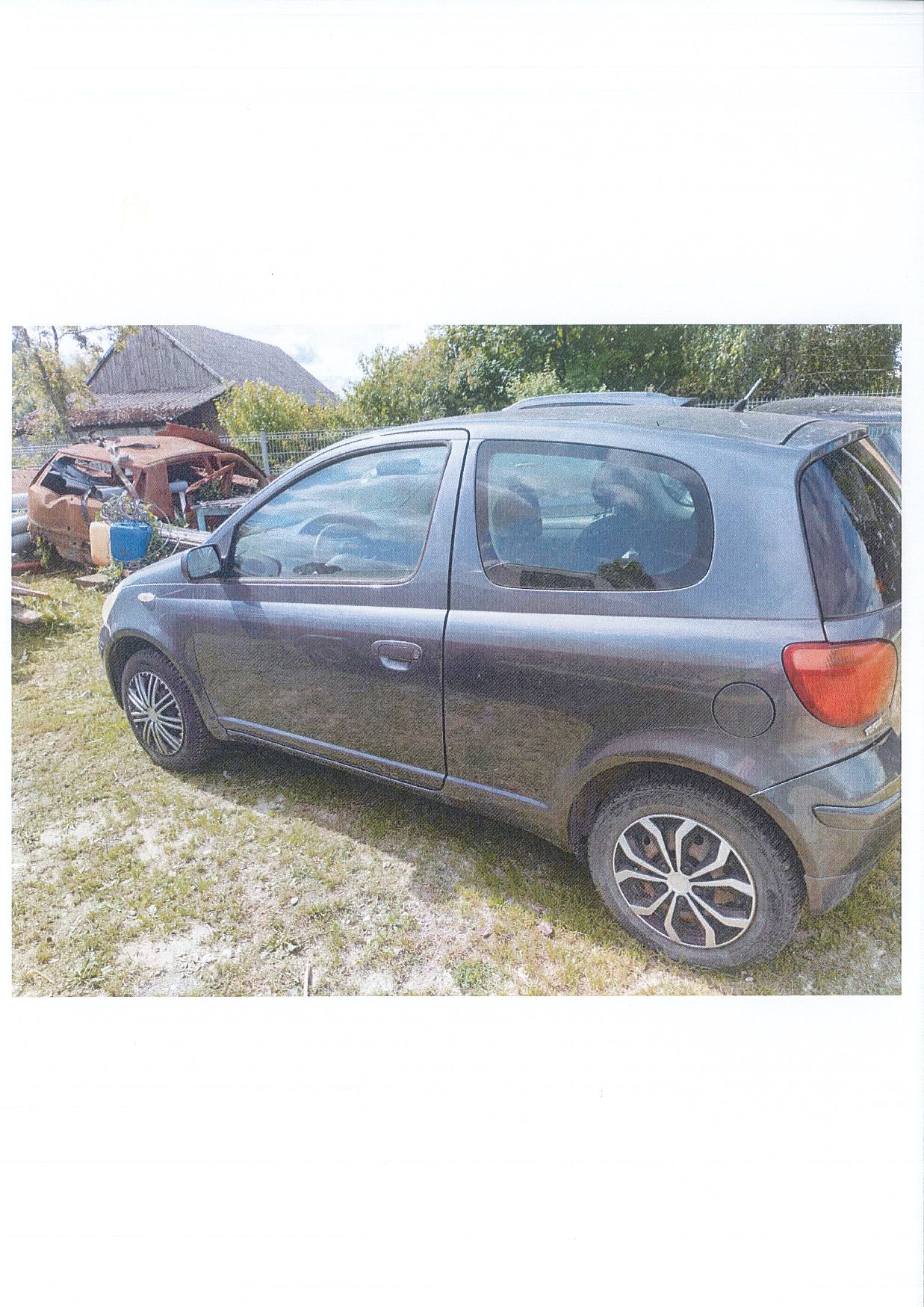 Lewy bok samochodu osobowego TOYOTA YARIS z widocznymi rysami na karoserii. Na kołach różne kołpaki.