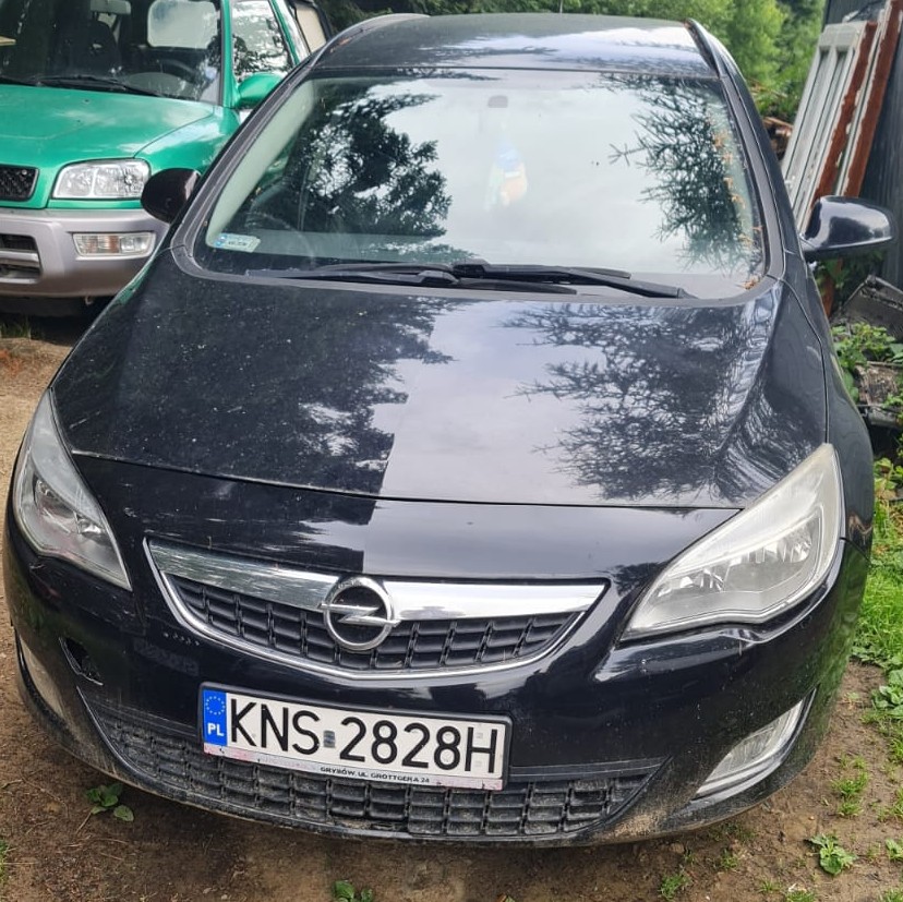 Przód granatowego pojazdu marki Opel Astra z polską tablicą rejestracyjną.