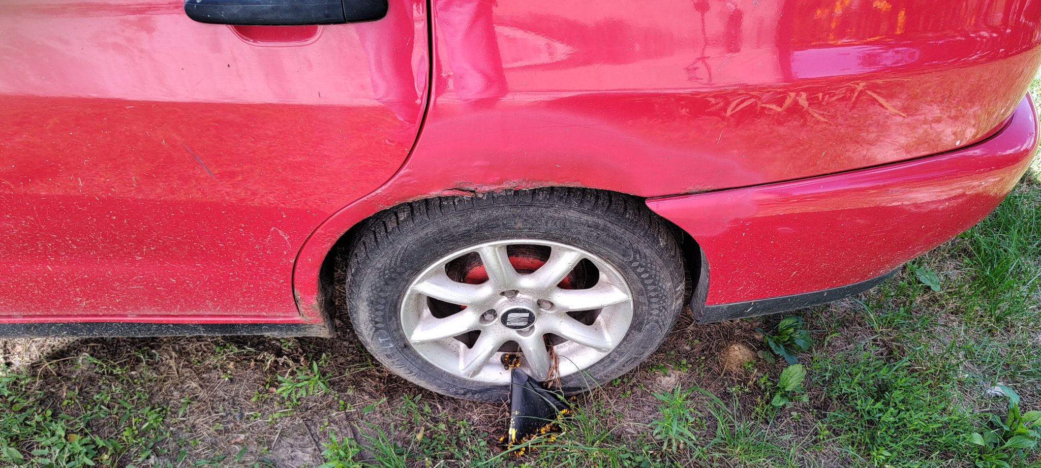Tylne koło pojazdu po lewej stronie wraz z widocznymi śladami korozji na blacharce nad nadkolem.