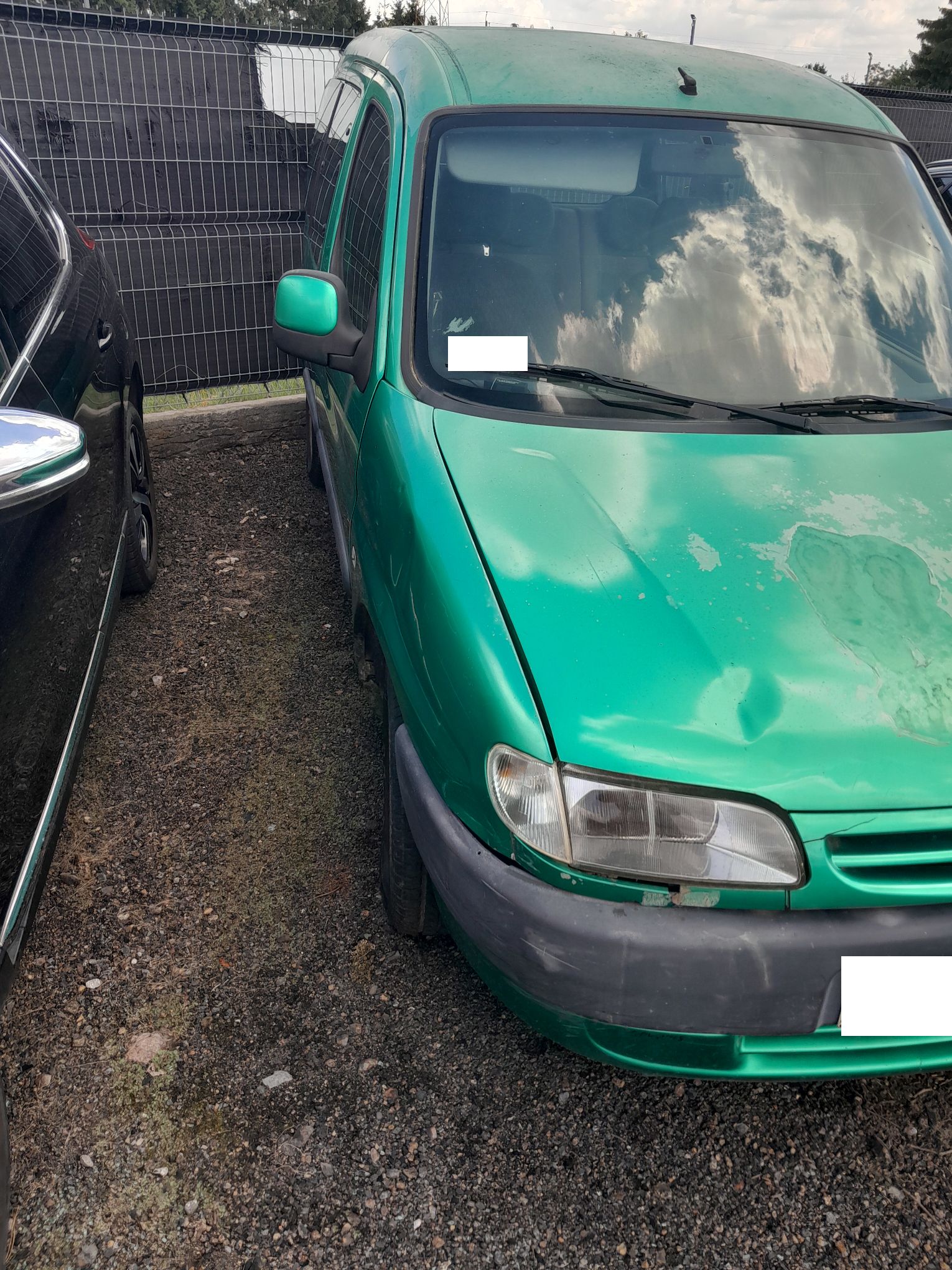 Zielony Citroen Berlingo, widziany od przodu prawej strony pojazdu, widoczne duże ubytki lakieru na masce
