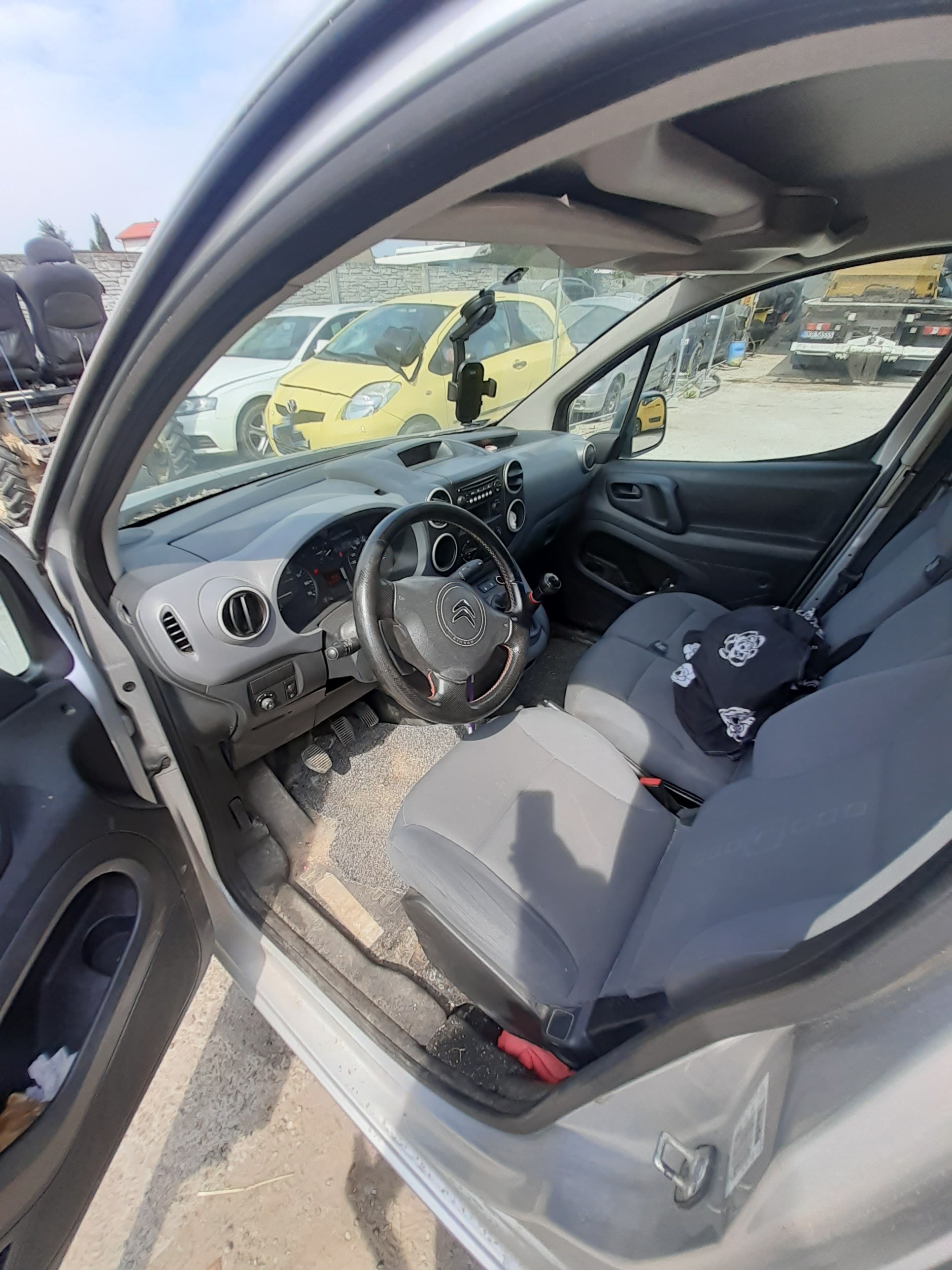 Wnętrze Citroëna Berlingo z szarymi fotelami, kierownicą z logo i deską rozdzielczą.