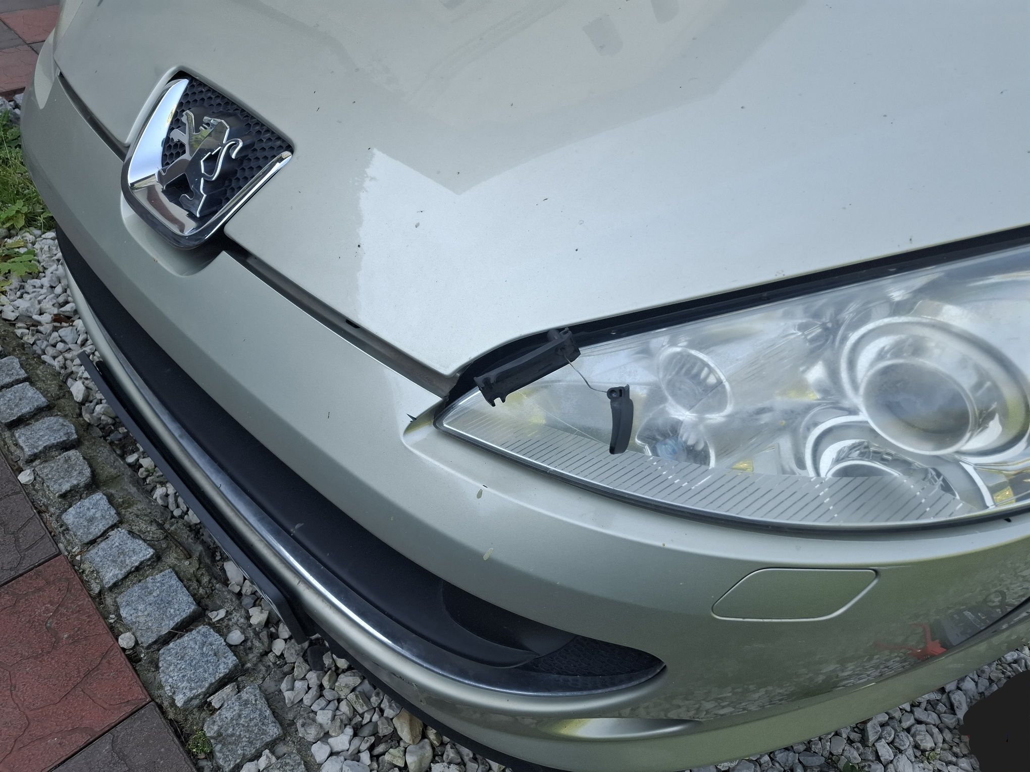 Zdjęcie przedstawia przednią, lewą część samochodu osobowego Peugeot 407. Na zdjęciu jest widoczna uszkodzona maska silnika.