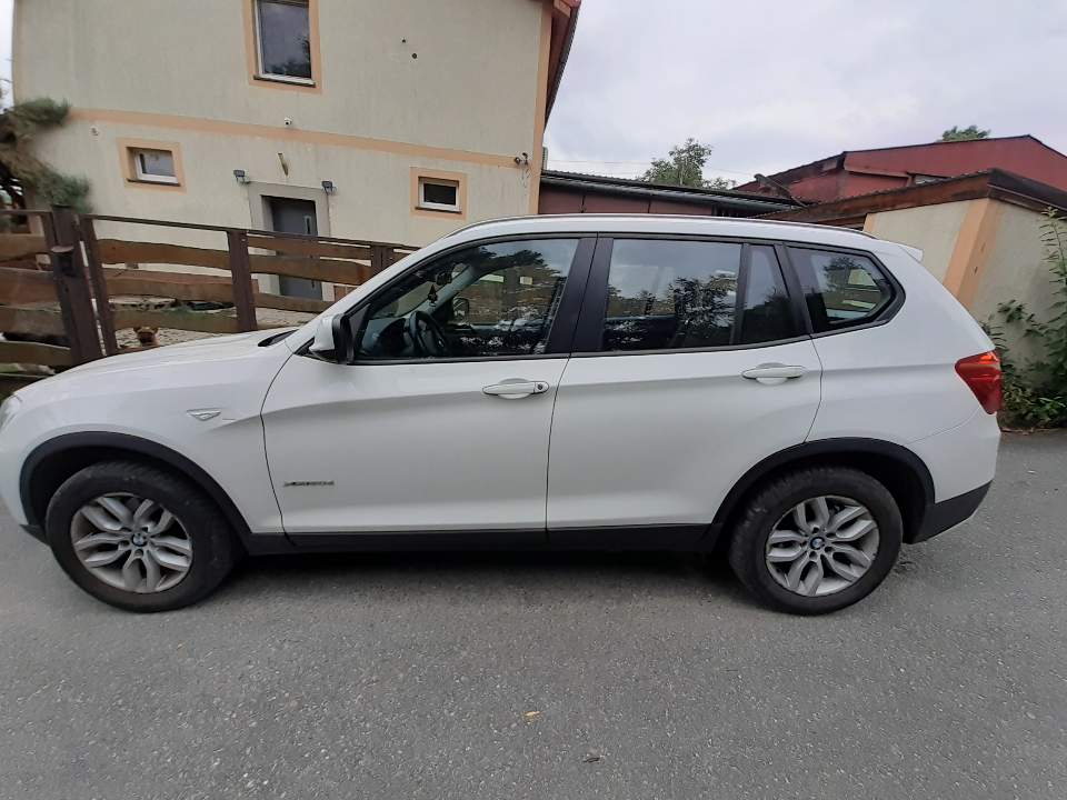 Biały samochód marki BMW X z polskimi tablicami rejestracyjnymi DKL 60791, widok z boku