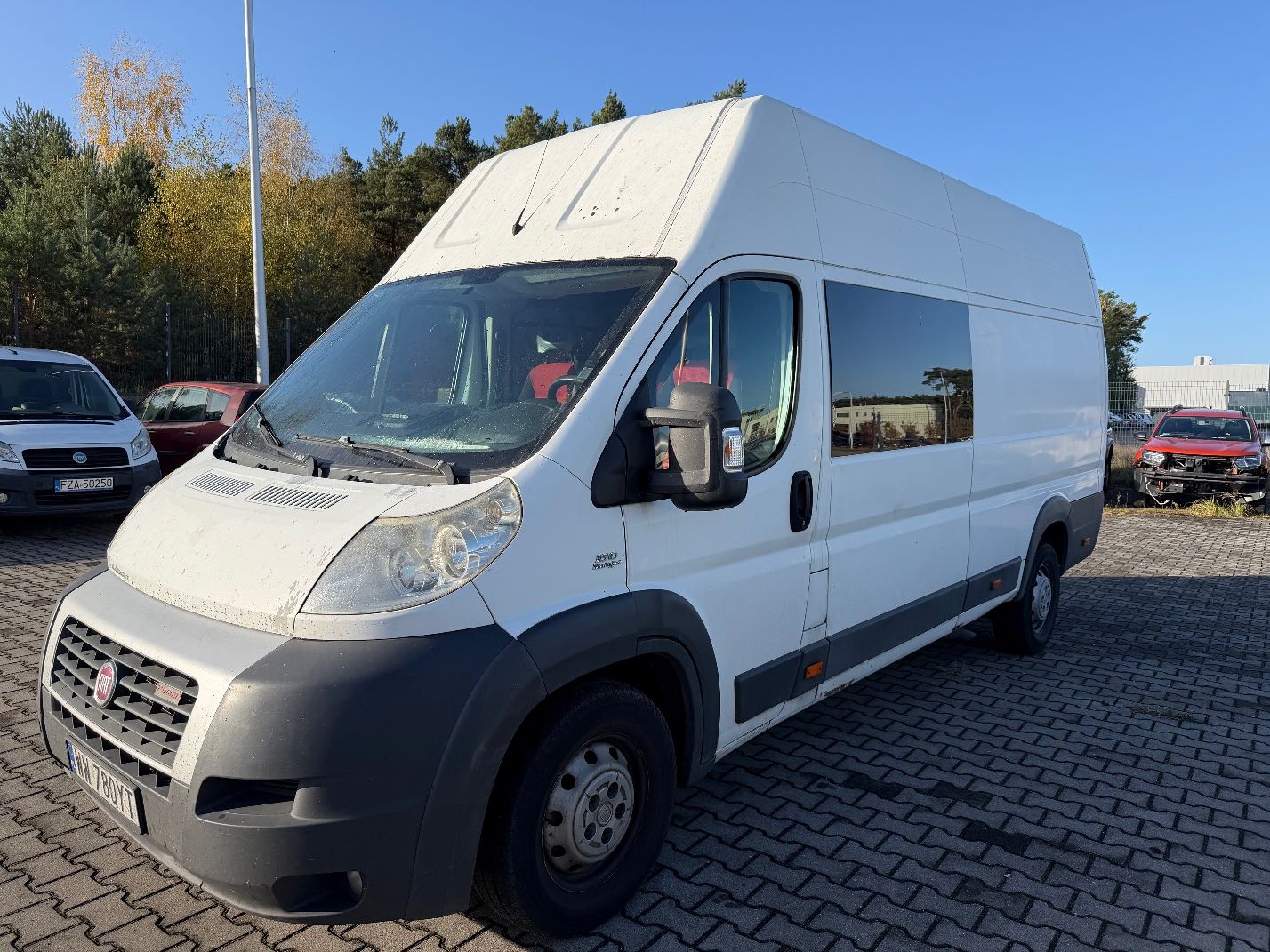 Biały Fiat Ducato, ujęcie lewej strony i przodu pojazdu pojazdu.