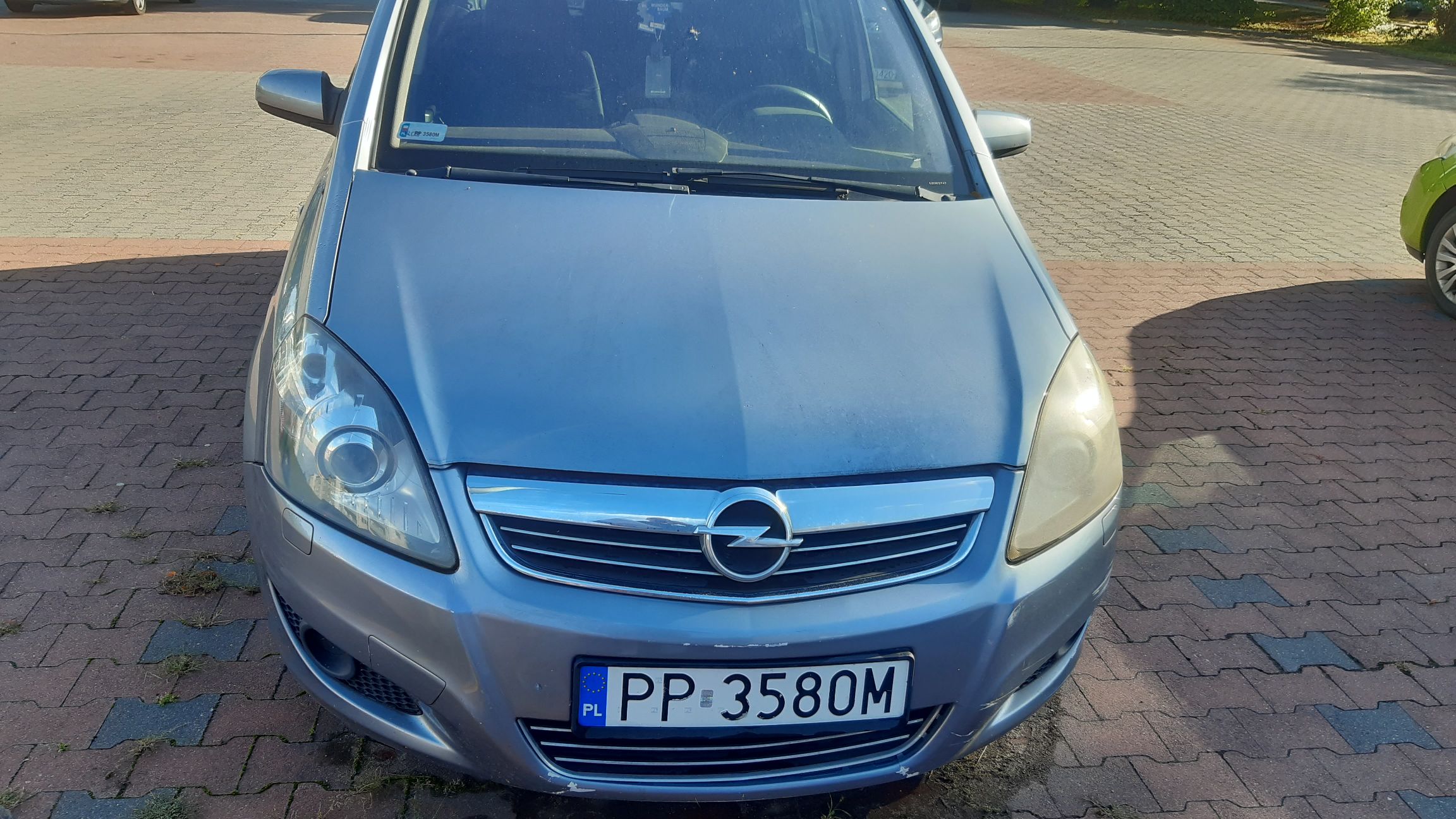 Srebrny samochód osobowy Opel Zafira widok z przodu