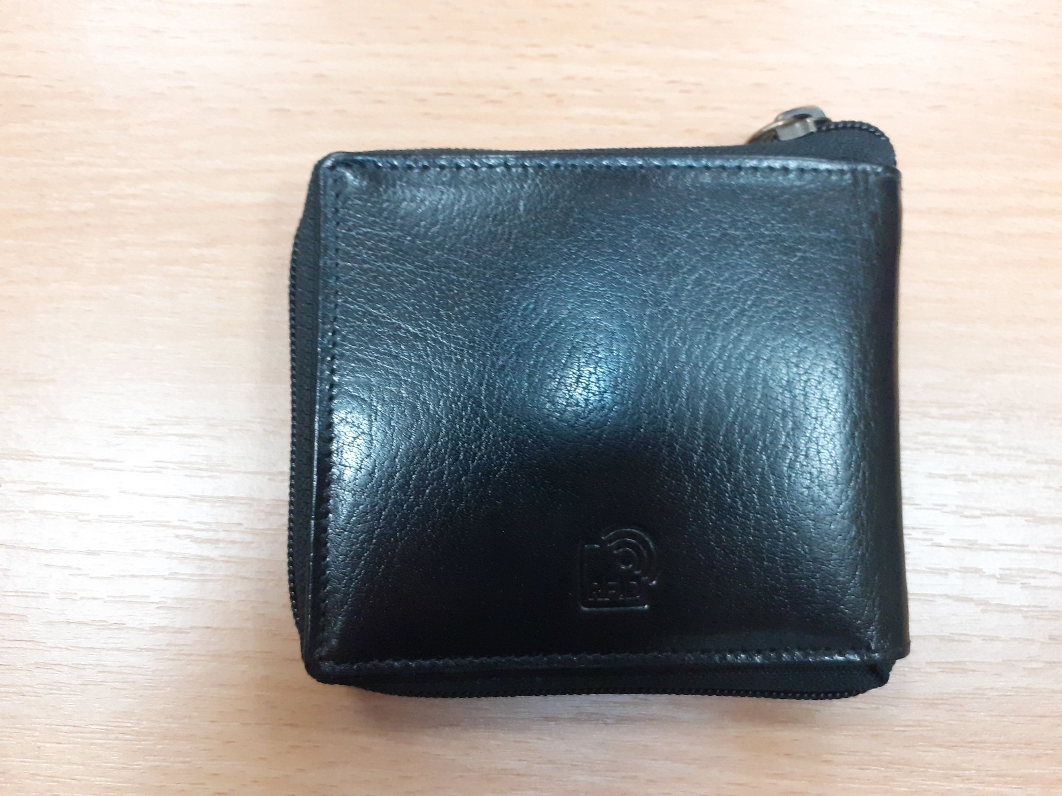 Portfel koloru czarnego z napisem wytłoczonym RFID zamykany na zamek.