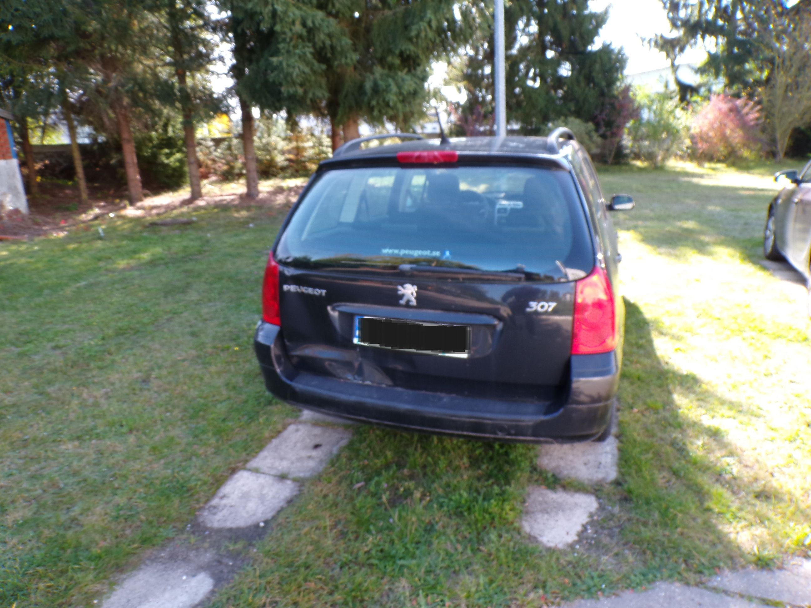 Tył samochodu osobowego Peugeot 307, koloru czarnego. Klapa od bagażnika uszkodzona, wgnieciona.