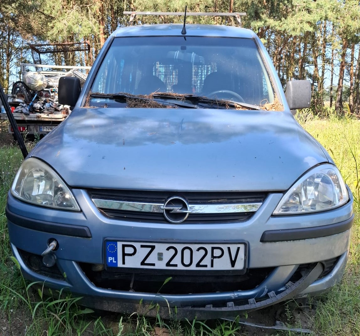 Przód srebrnego Opla Combo z widocznymi uszkodzeniami maskownicy zderzaka oraz halogenów
