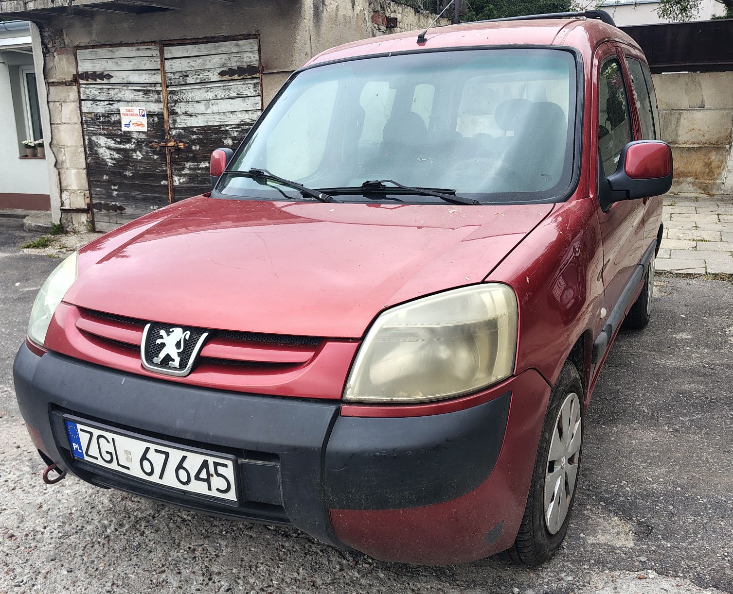 Widok od przodu, brak wgnieceń, widoczne ślady korozji na zderzaku; pojazd stoi na kołach.