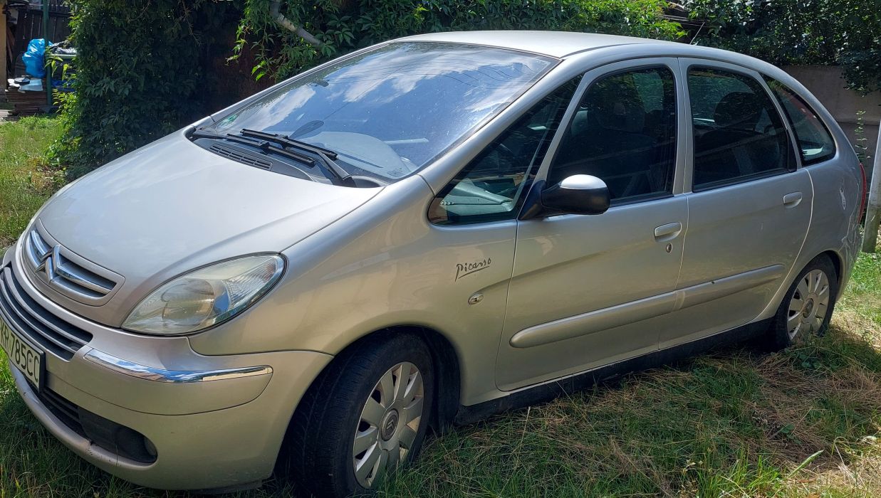 Przód i lewy bok srebrnego Citroena Xsara Picasso, widoczne otarcia na zderzaku