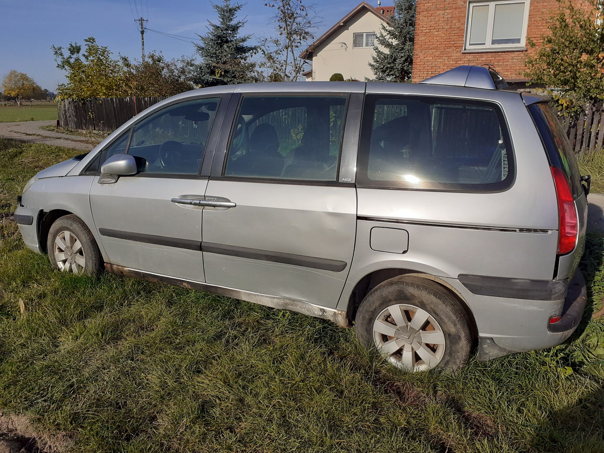Srebrny samochód osobowy Peugeot typu minivan widoczny z boku ze śladami korozji na progu.