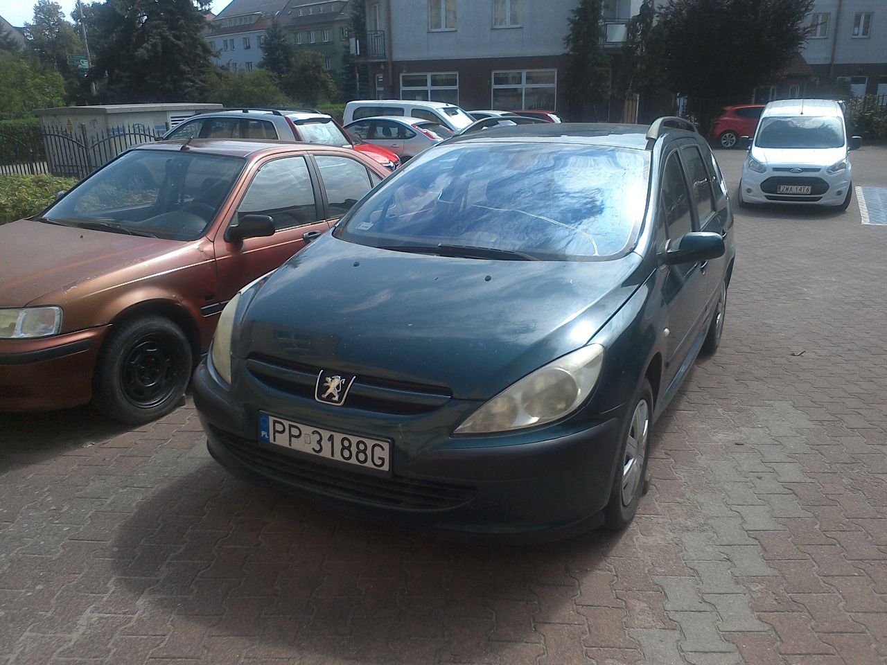 Widok zielonego Peugeota 307 z przodu. Pęknięta przednia szyba.