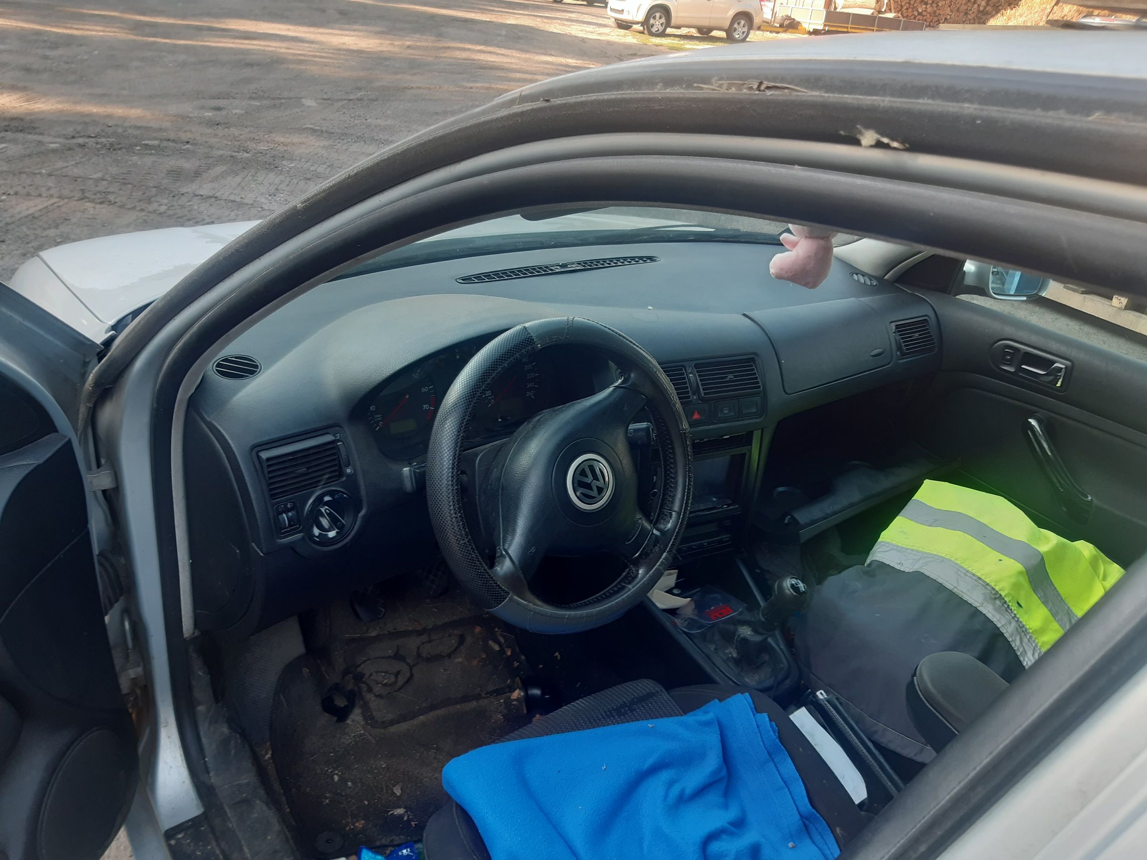 Wnętrze Volkswagena Golfa IV z widoczną deską rozdzielczą, kierownicą z logo VW oraz siedzeniami, widoczne ślady użytkowania.