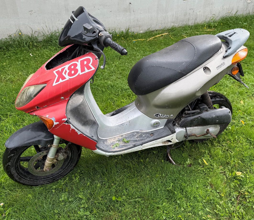 Skuter w kolorze czerwono srebrnym. Widok z lewej strony motoroweru.