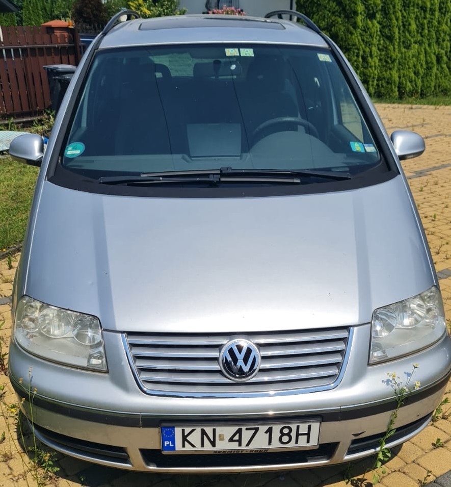 Przód srebrnego samochodu marki Volkswagen Sharan z polskimi tablicami rejestracyjnymi.