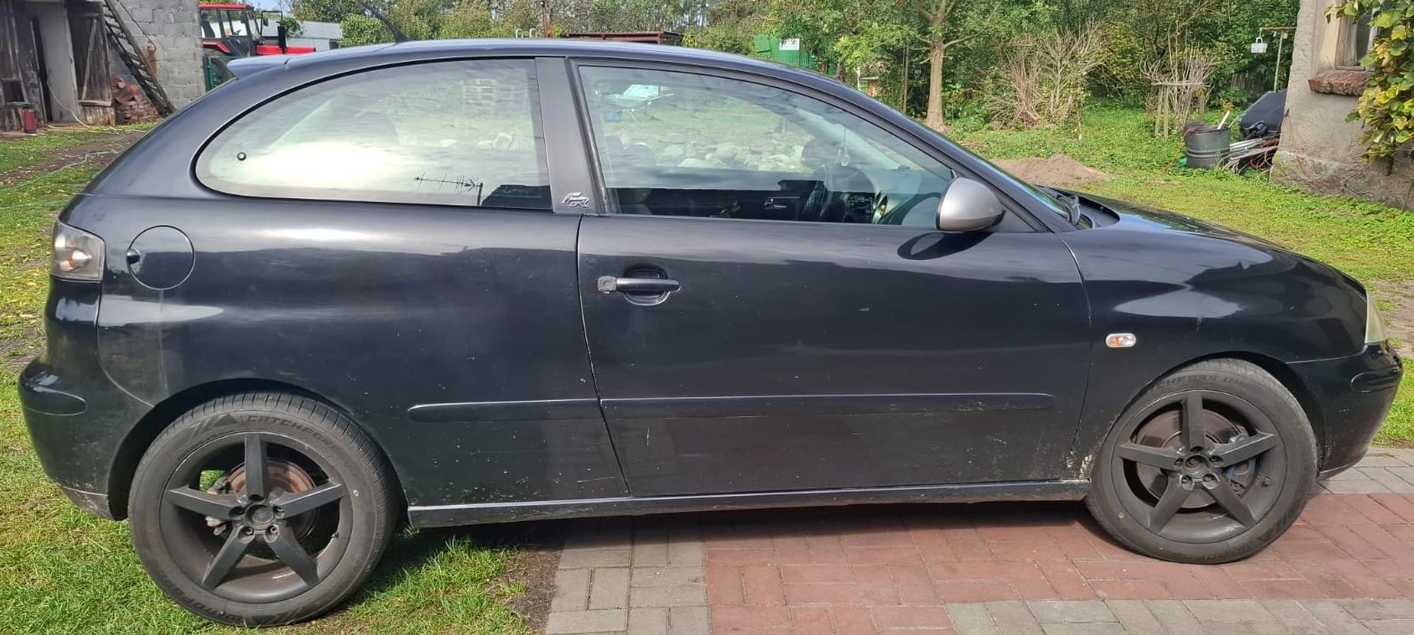 Prawy bok czarnego Seata Ibizy z widocznymi oznakami korozji na progu