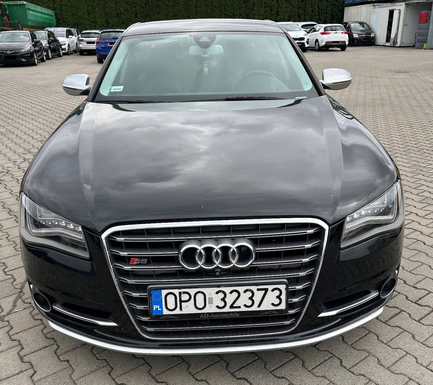 Przód pojazdu. Na przodzie jest duży, chromowany grill z czterema pierścieniami marki Audi oraz oznaczeniem S8.