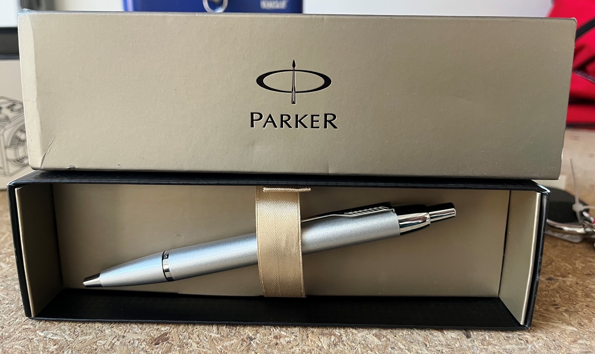 Srebrny długopis Parker w papierowym opakowaniu.
