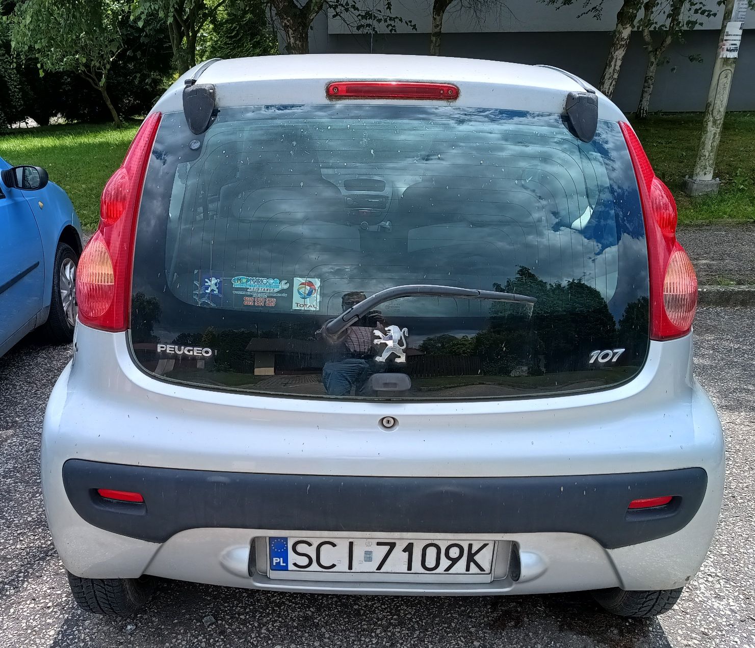 Zdjęcie przedmiotu. Widok przedstawia tył samochodu koloru srebrnego z tablicą rejestracyjną