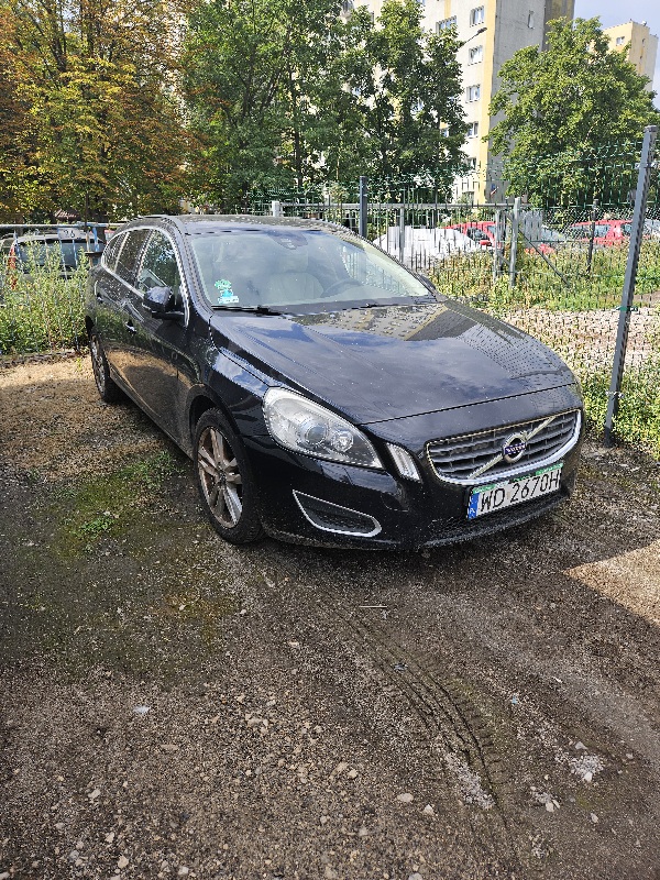 Samochód marki Volvo koloru czarnego. Widok przedniego lewego boku.