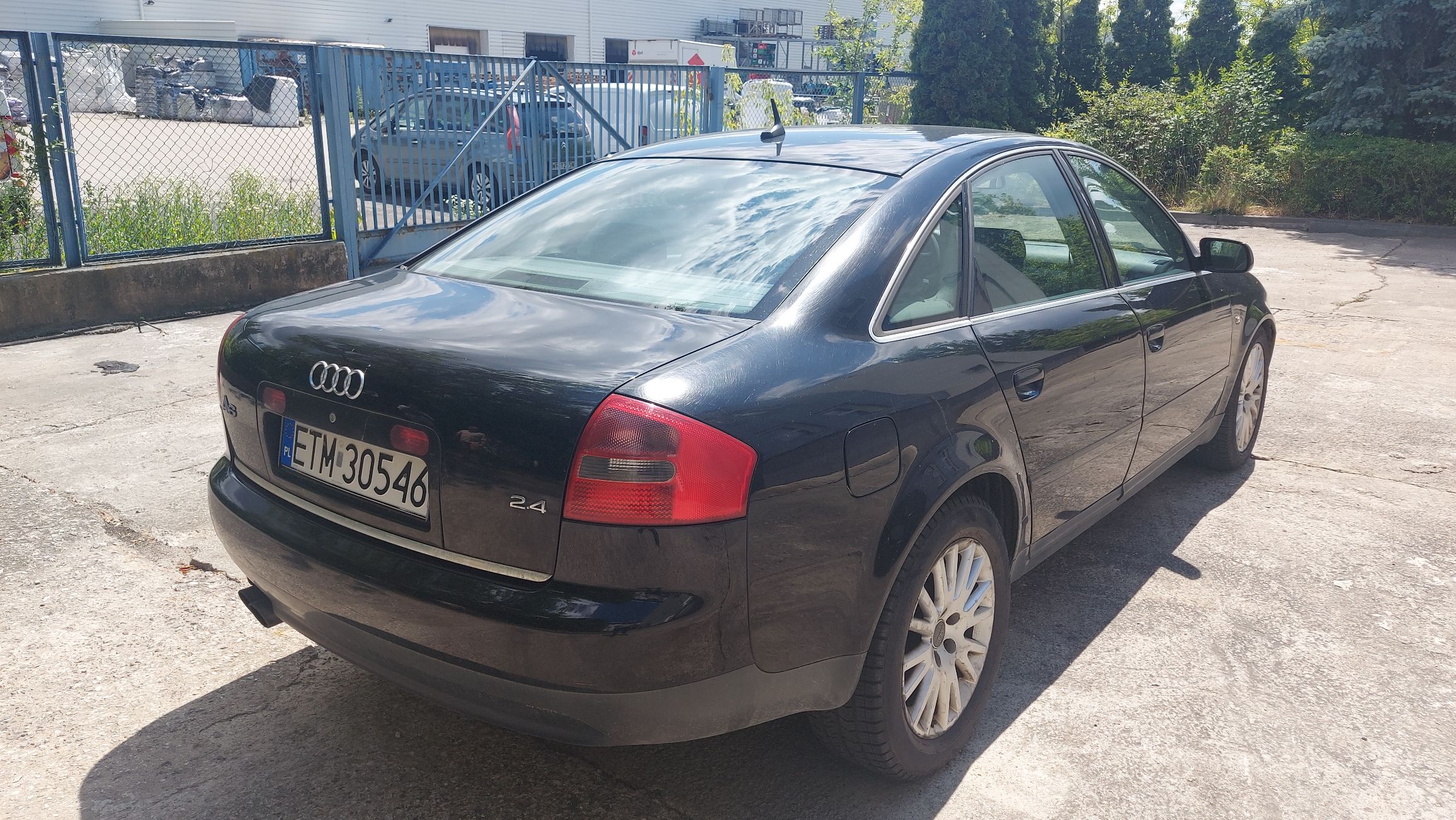 Tył i prawy bok czarnego Audi A6 C5 sedan. Widoczne oznaczenie silnika 2.4, tablica rejestracyjna ETM 30546, alufelgi.
