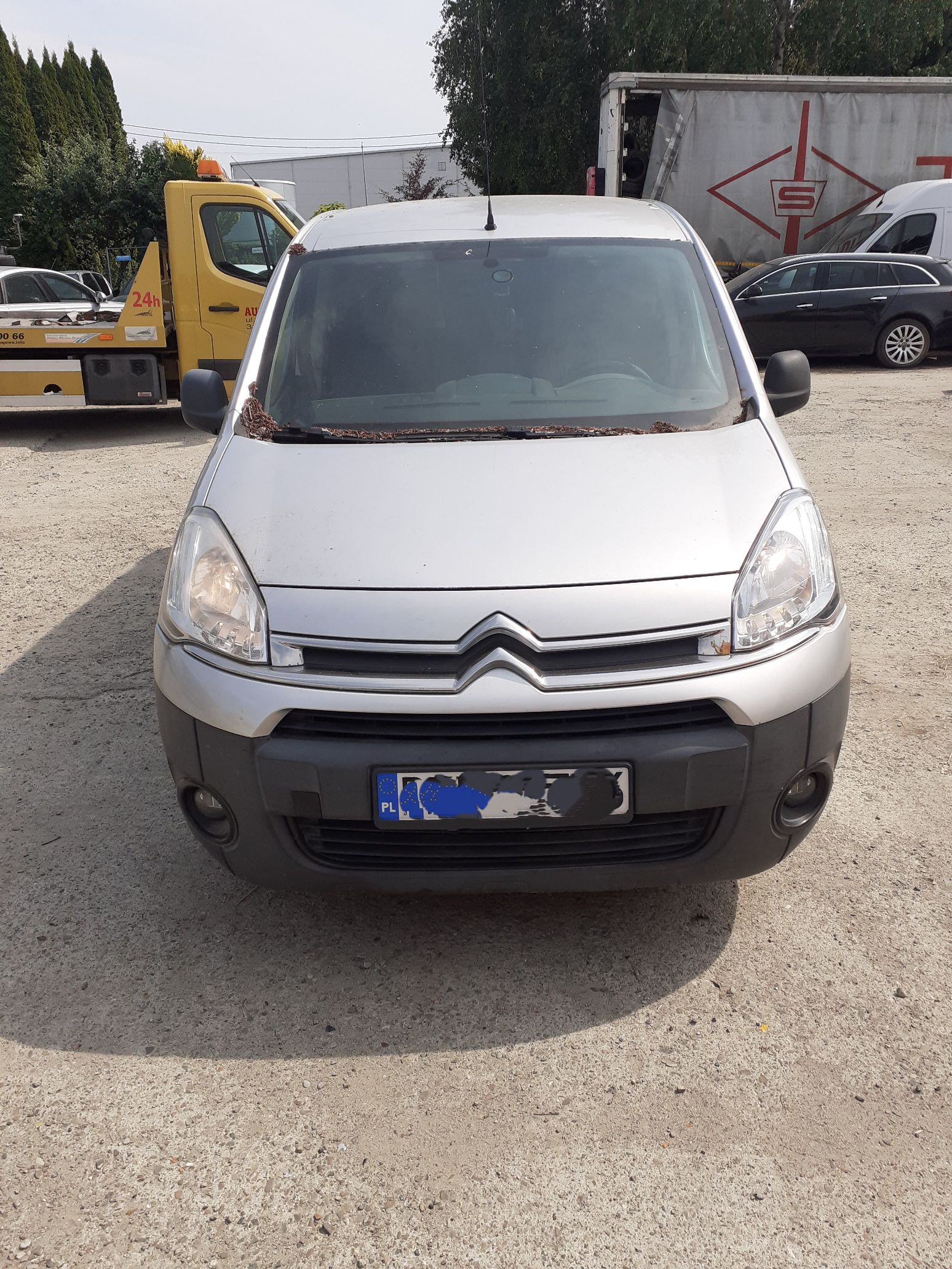 Srebrny dostawczy Citroën Berlingo, widziany od przodu z charakterystycznym logo marki na grillu oraz czarnym zderzakiem.