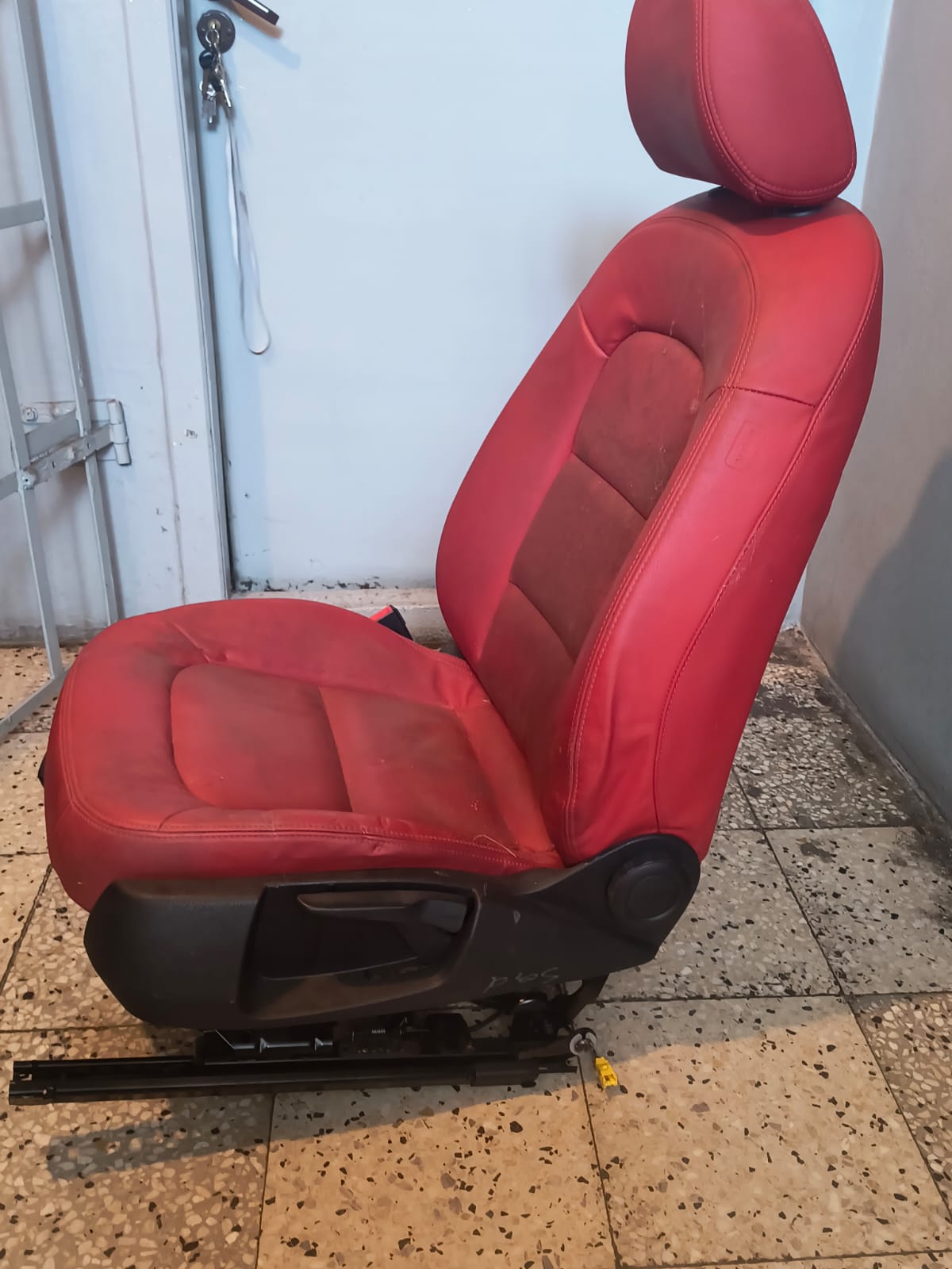 Przedni fotel samochodowy w kolorze czerwonym, ustawiony w pozycji bocznej, czerwone obicie ze skóry